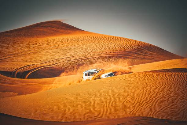 A car driving through a scenic desert landscape, descending a hill in the background